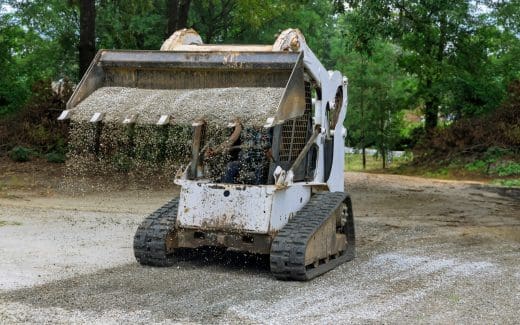 In construction work, bobcat mini loader is moving a bucket full of crushed stone gravel